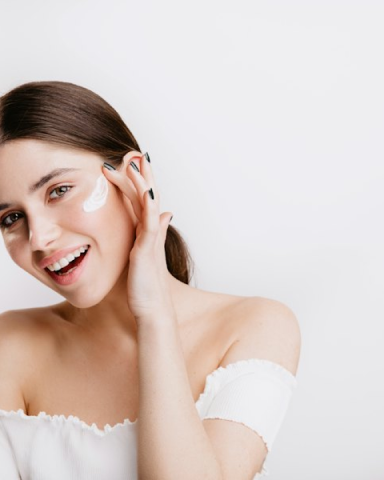 Smiling client applying cream to her face