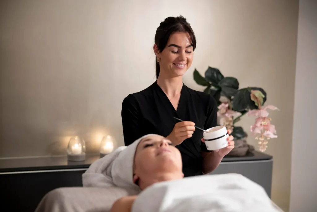 Skin specialist applying a facial mask to a client in a calm treatment room